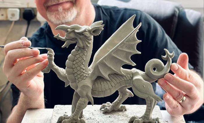 The photo depicts Richard in his studio at the shop, sculpting an impressive dragon.